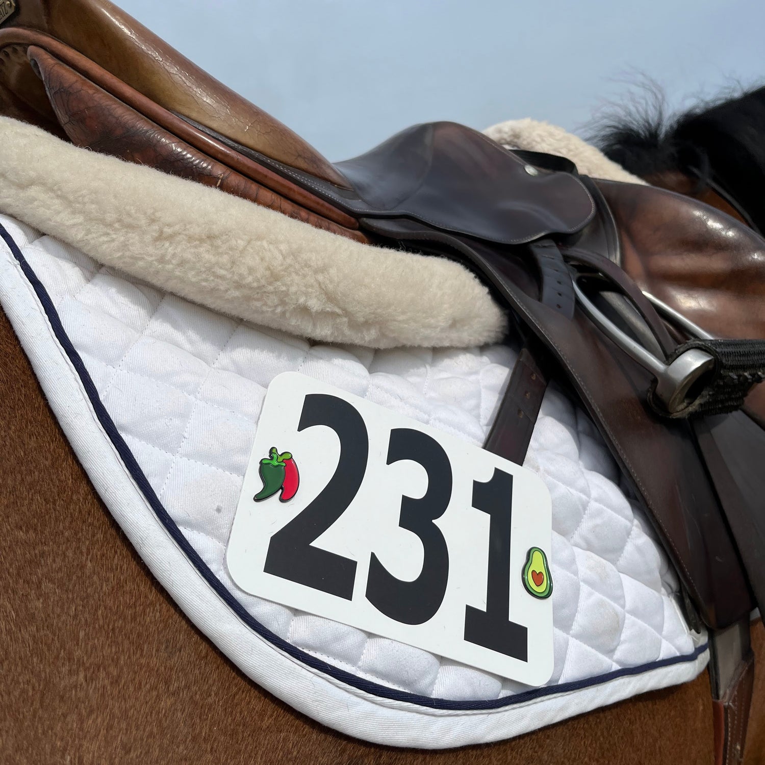 Pinsnickety Chili Peppers and Avocado horse show number pads mixed together on a saddle pad