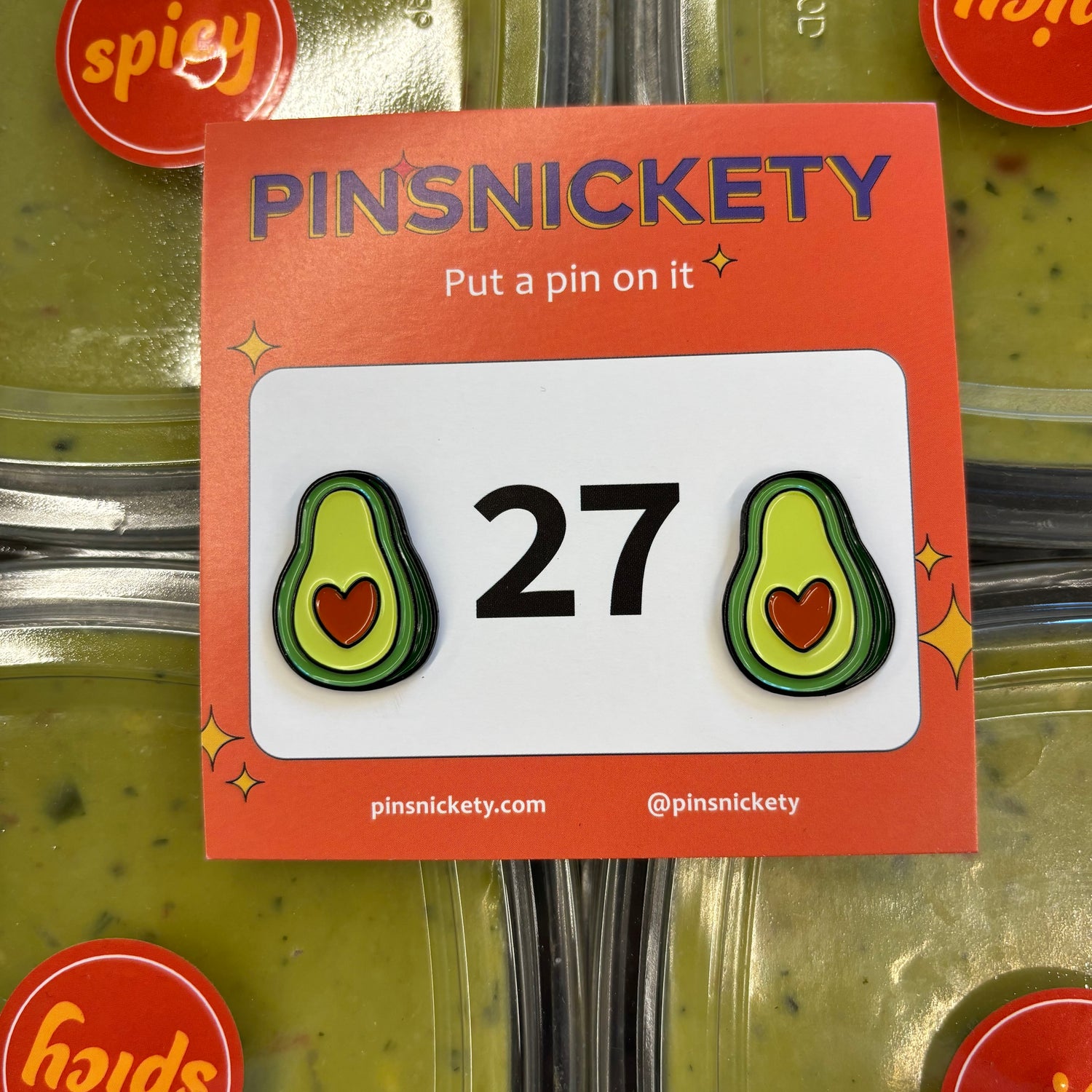 pinsnickety avocado horse show number pins on a stack of spicy guacamole containers in a store