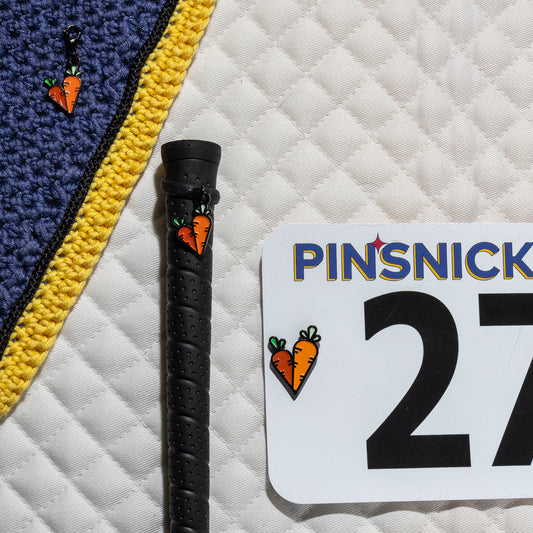 A saddle pad, bonnet and whip decorated with matching Carrots Pinsnickety horse show number pins, a bridle charm and a crop charm.