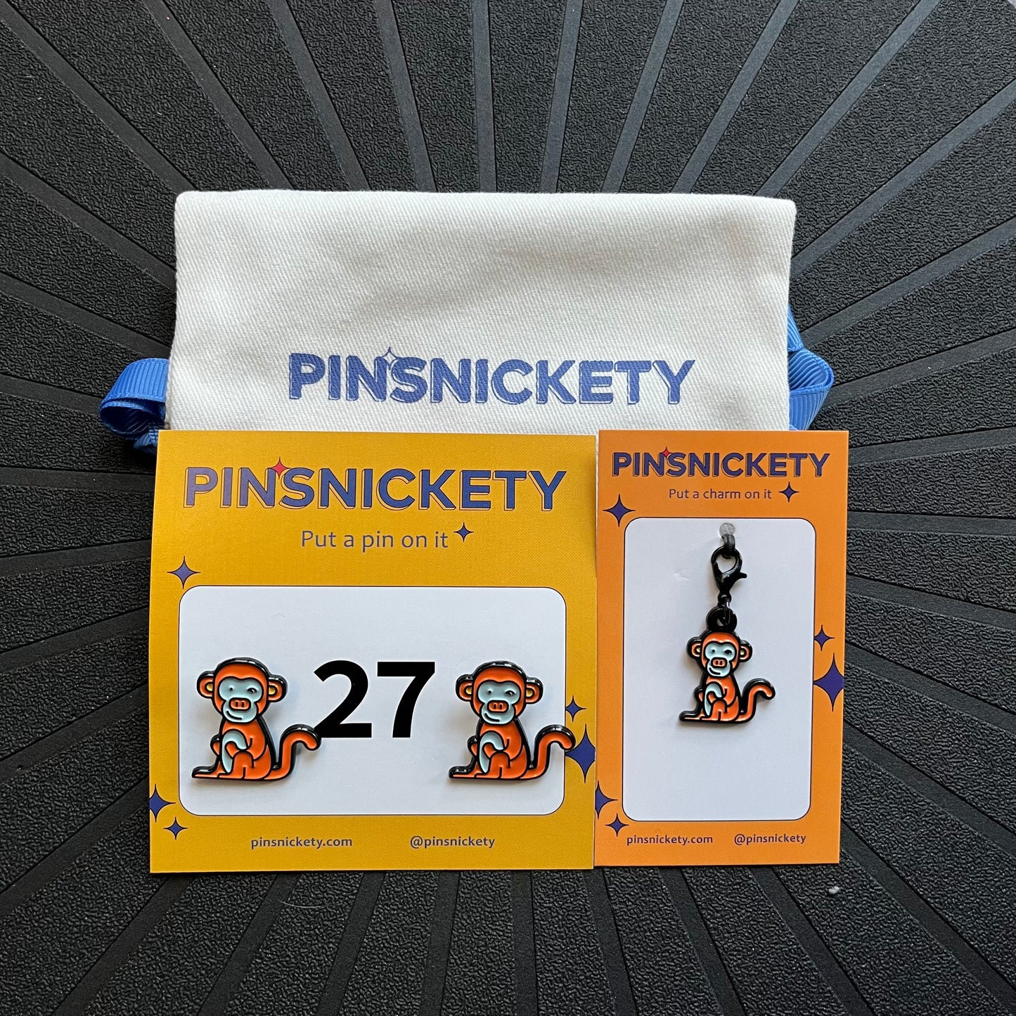 pinsnickety monkey matching set, featuring monkey horse show number pins, a monkey bridle charm, and a twill storage bag, all displayed on a black background