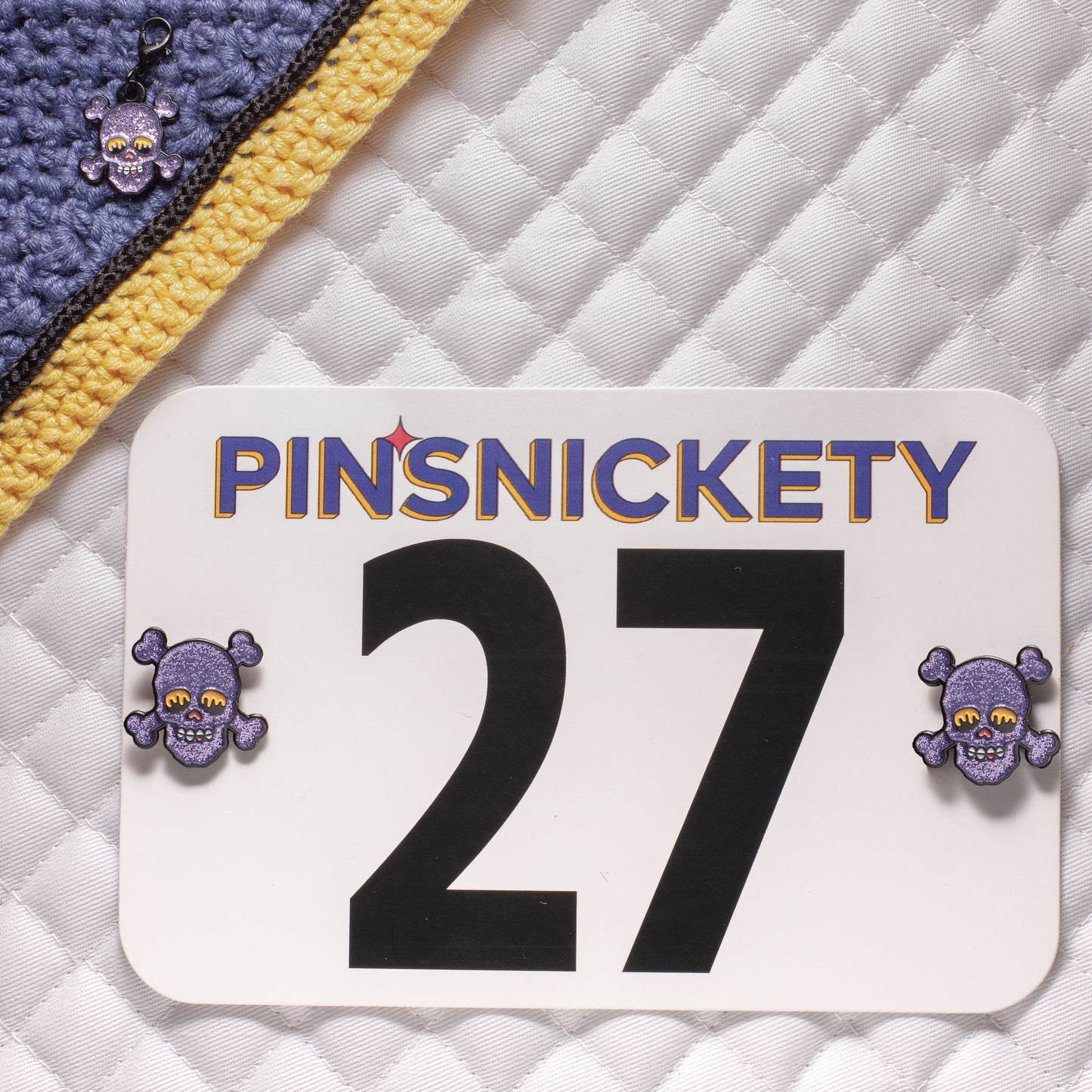 Pinsnickety skull horse show number pins on a saddle pad and skull braid and bridle charm on a bonnet