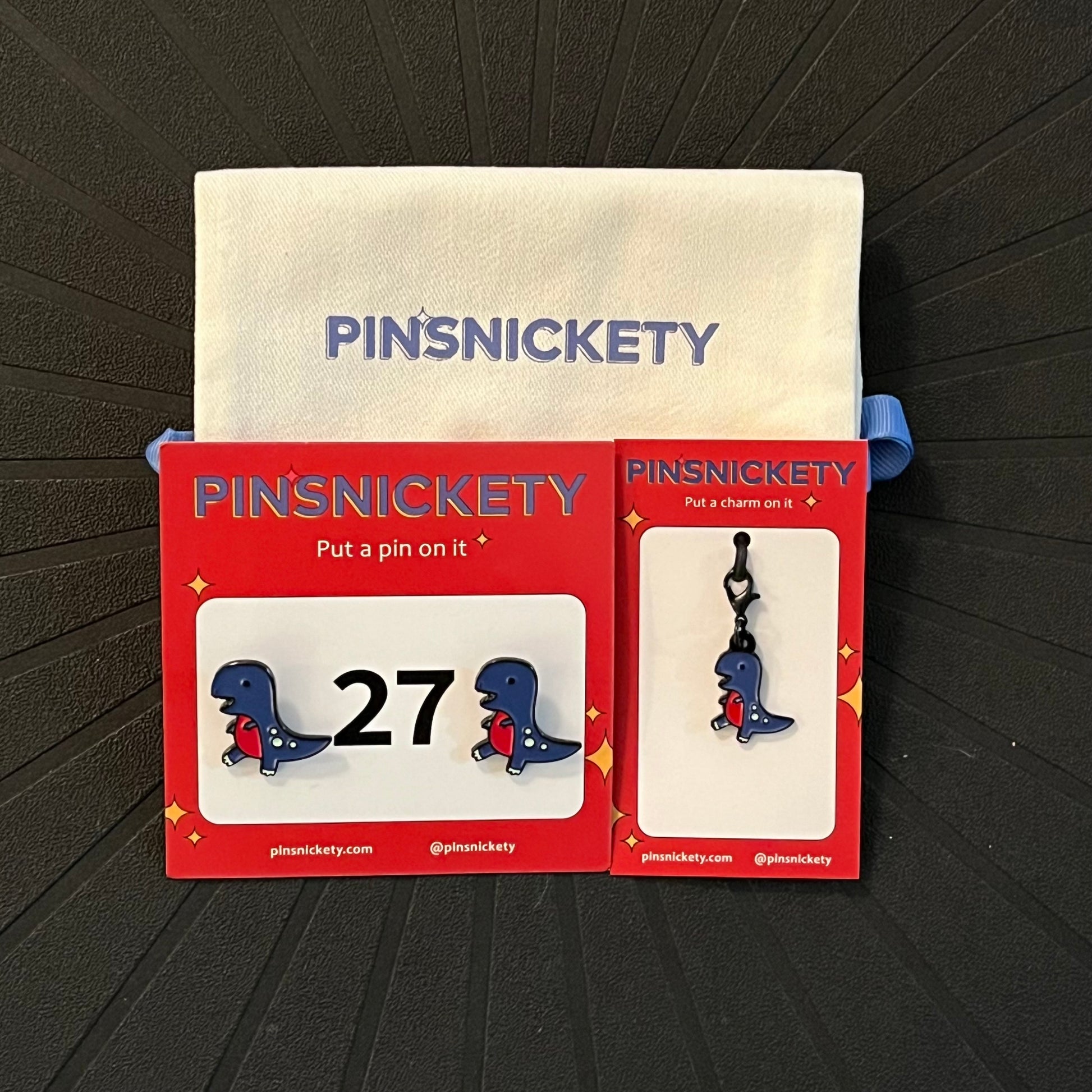 Pinsnickety matching set featuring T-rex horse show number pins, a t-rex braid and bridle charm, and a pinsnickety deluxe twill storage bag