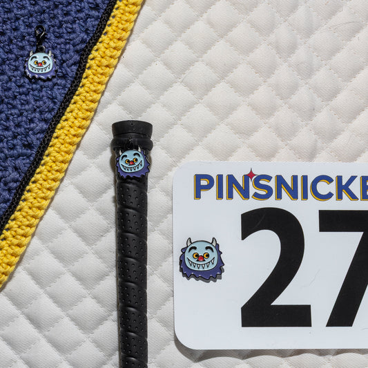 A saddle pad, bonnet and whip decorated with matching Wild Thing Pinsnickety horse show number pins, a bridle charm and a crop charm.