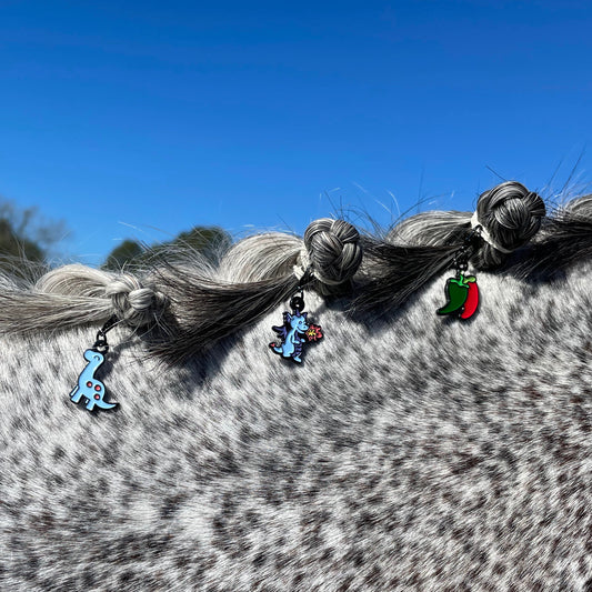 pinsnickety brontosaurus, dragon, and chili pepper bridle charms in a grey horse's braided mane