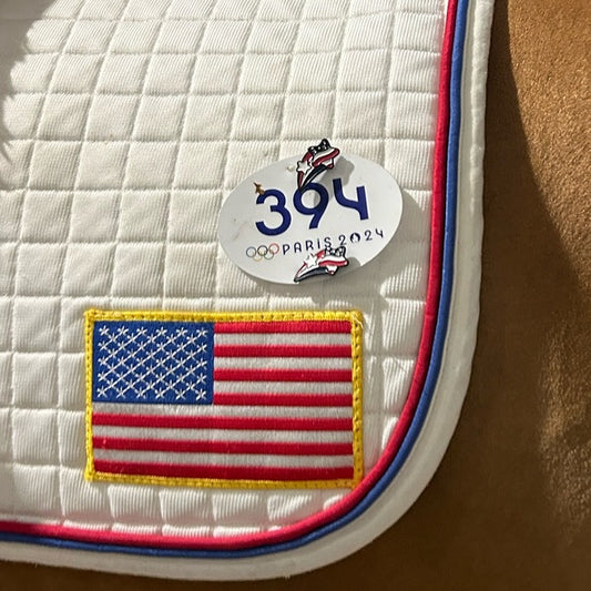 pinsnickety stars and stripes flag horse show number pins on a McLain Ward's saddle pad at the 2024 Paris olympics