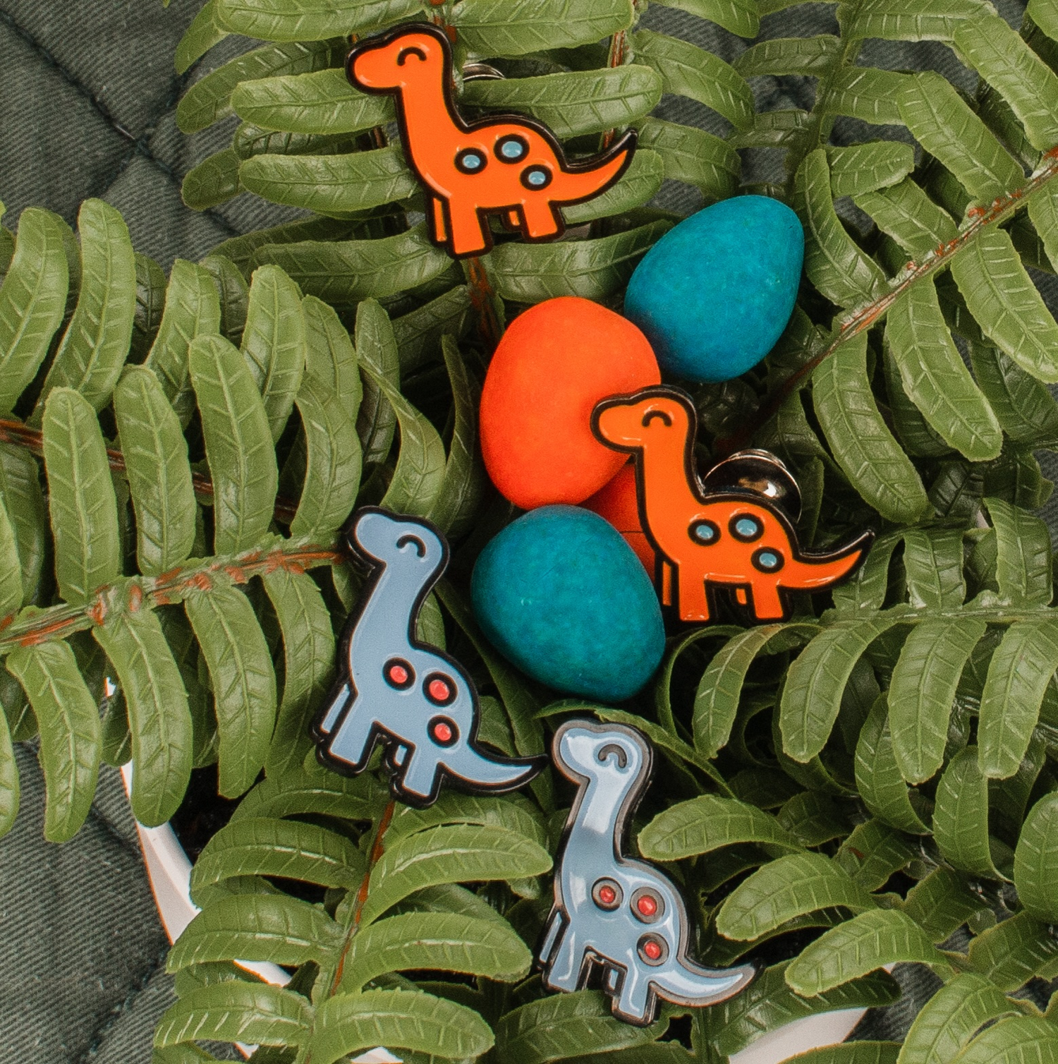 pinsnickety brontosaurus horse show number pins in a nest of ferns, including both orange and classic blue colorways