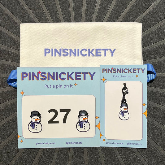 pinsnickety snowman set, featuring a snowman horse show number pin, a snowman bridle charm and a Pinsnickety twill storage bag, on a black background