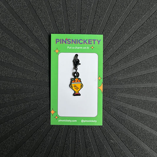 Pinsnickety trophy charm on a black textured background