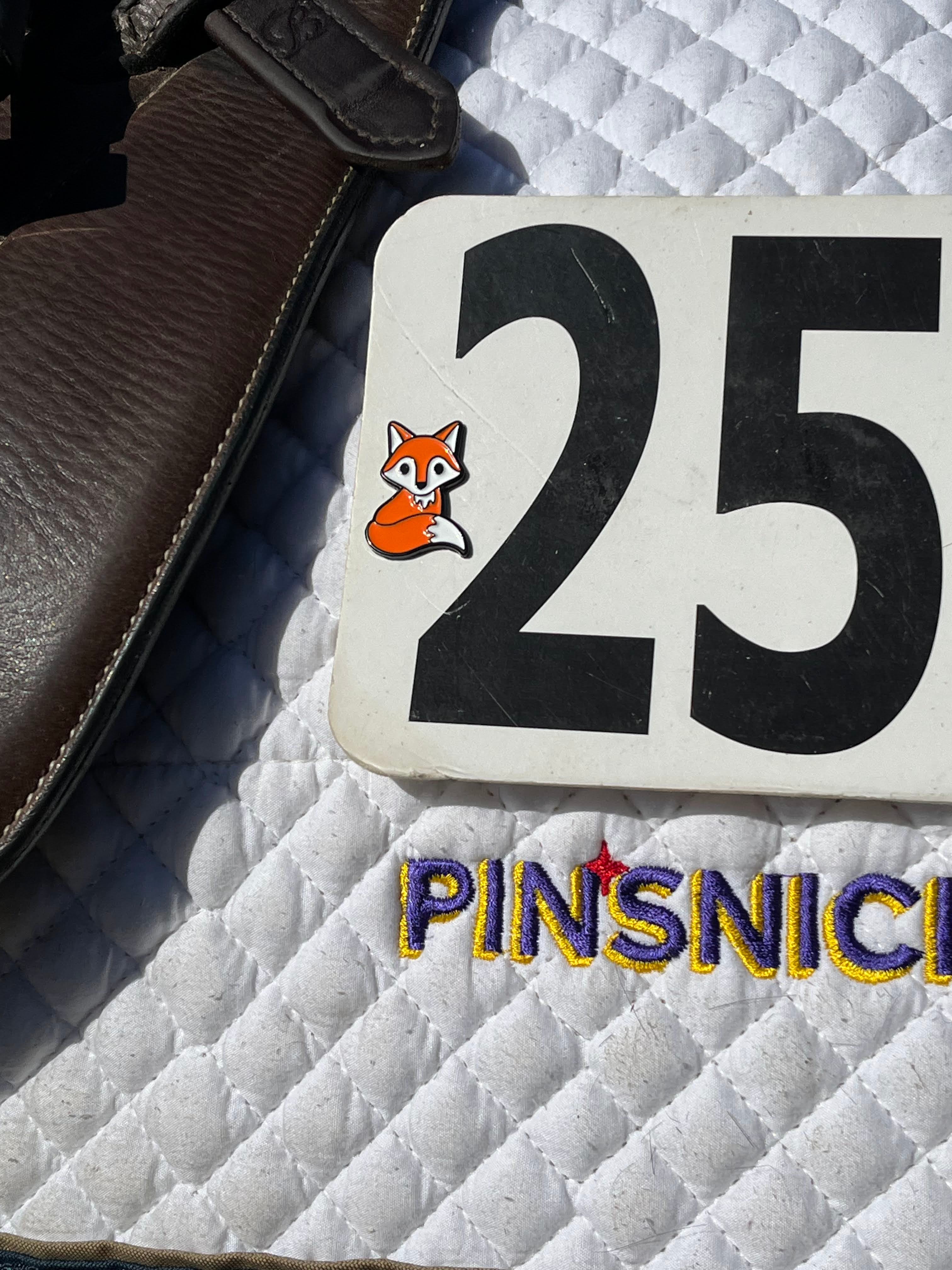 a pinsnickety fox horse show number pin on a saddle pad