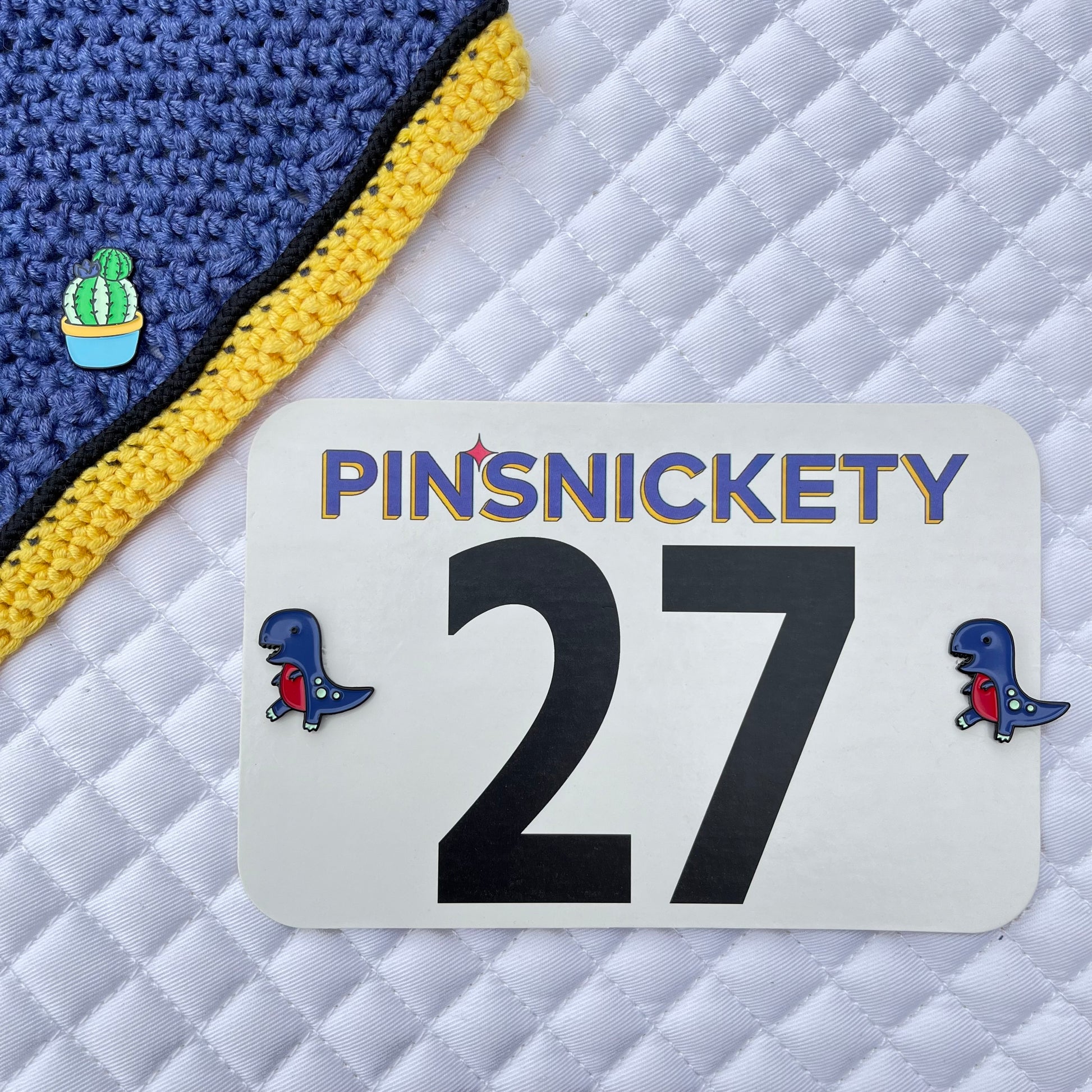 Pinsnickety cactus horse show number pin on a fly bonnet and t-rex horse show number pins on a saddle pad