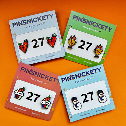 four sets of Pinsnickety horse show number pins including carrots on an orange background.