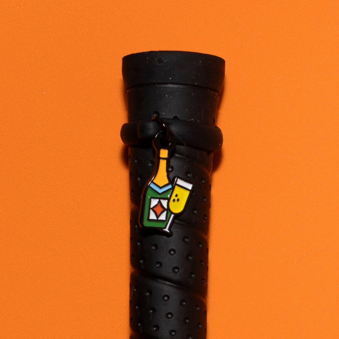Pinsnickety Champagne crop charm on a whip handle in front of a colored background