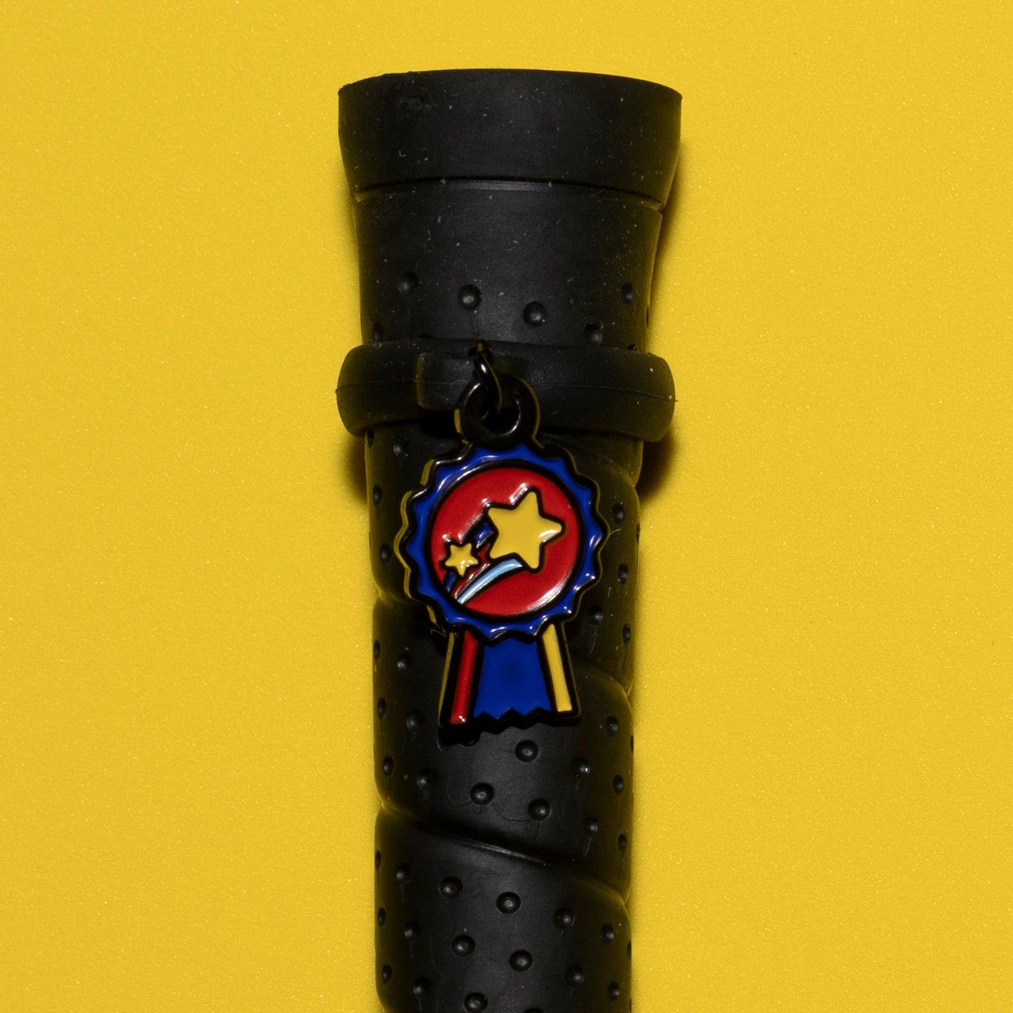 Pinsnickety Champion crop charm on a whip handle in front of a colored background