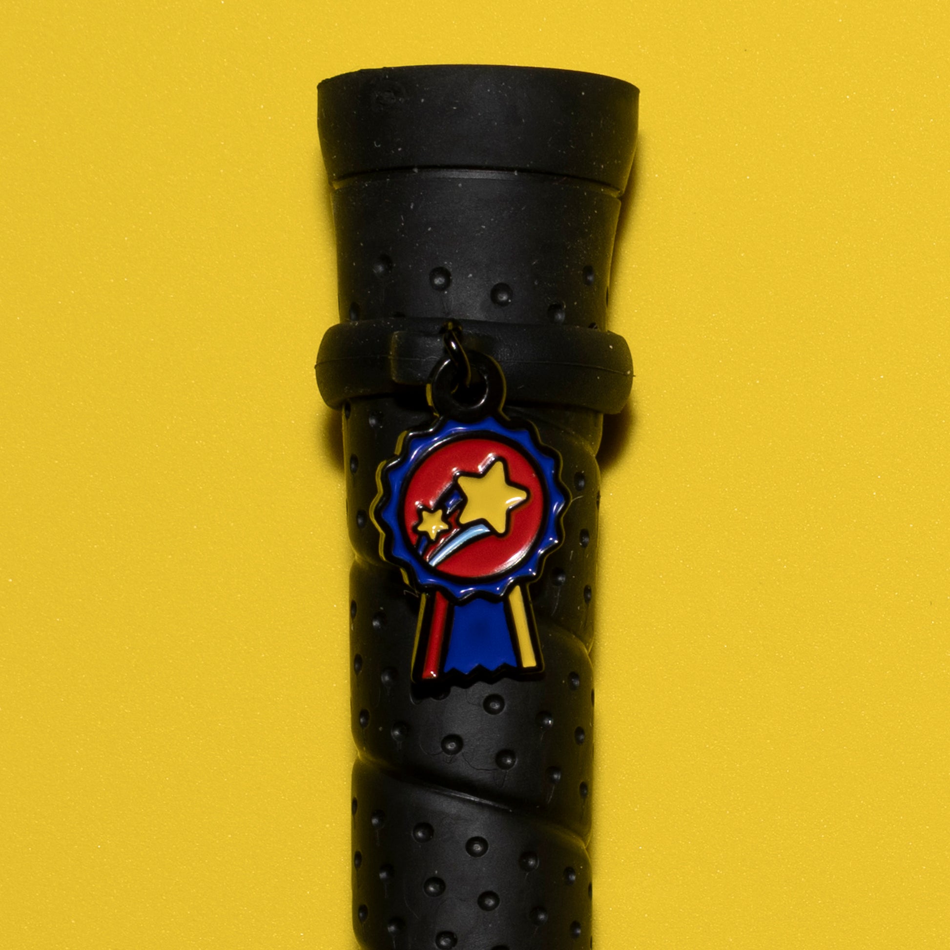 Pinsnickety Champion crop charm on a whip handle in front of a colored background