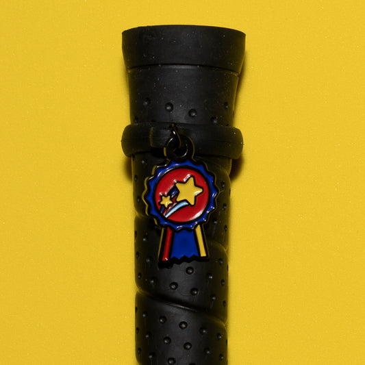 Pinsnickety Champion crop charm on a whip handle in front of a colored background