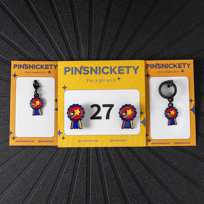 A matching triple combination set with Pinsnickety Champion horse show number pins, a bridle charm, and a crop charm in their product packaging on a black background.