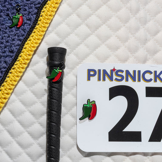 A saddle pad, bonnet and whip decorated with matching Chili Peppers Pinsnickety horse show number pins, a bridle charm and a crop charm.