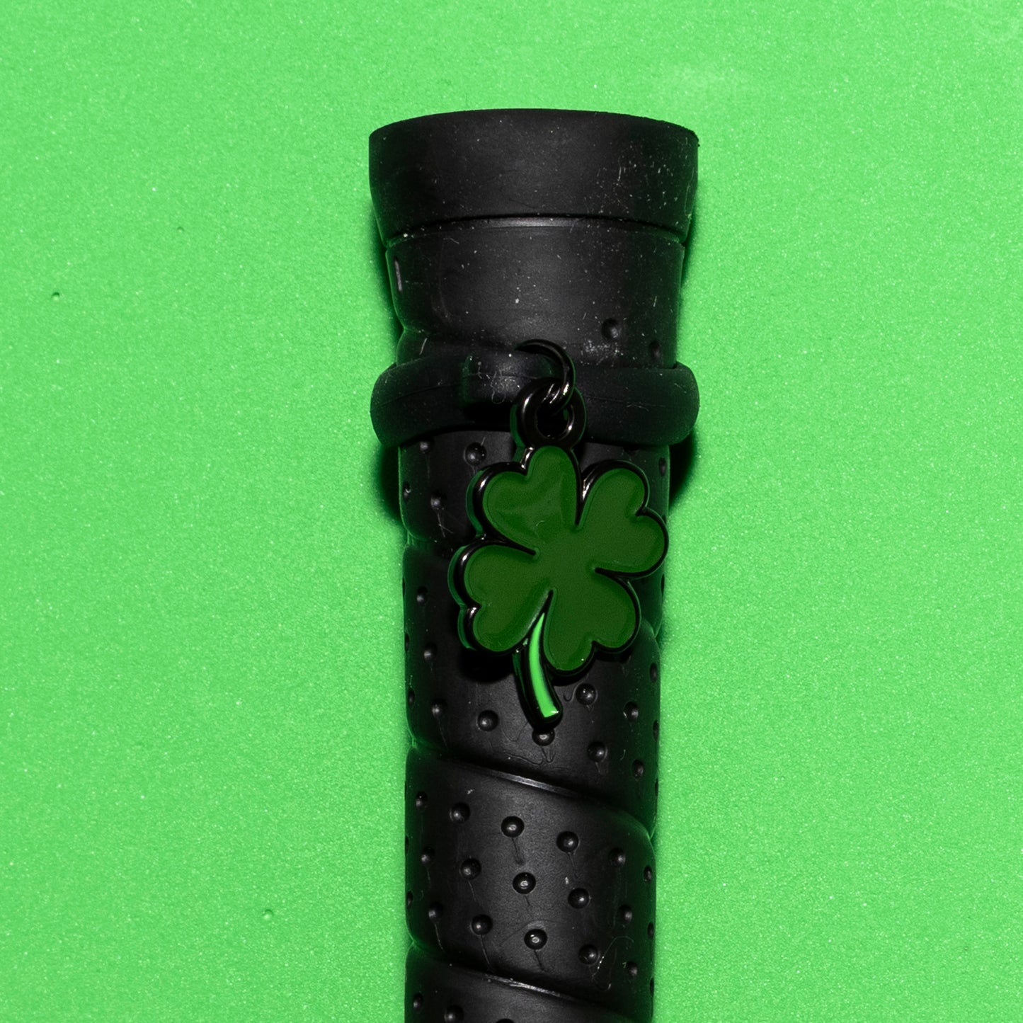 Pinsnickety Clover crop charm on a whip handle in front of a colored background