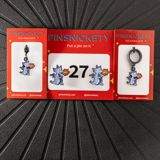 A matching triple combination set with Pinsnickety Dragon horse show number pins, a bridle charm, and a crop charm in their product packaging on a black background.