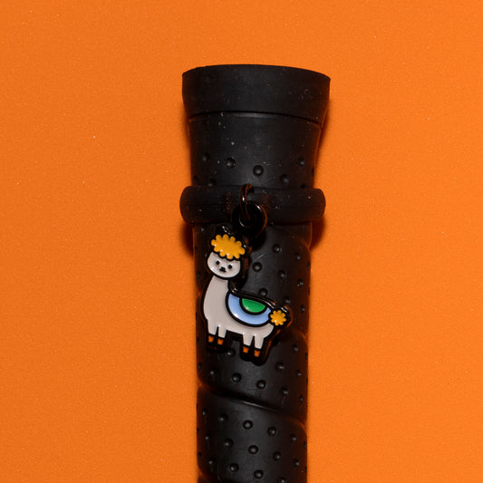 Pinsnickety Drama llama crop charm on a whip handle in front of a colored background