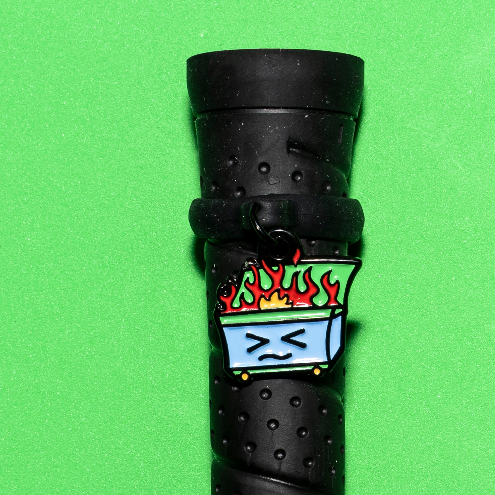 Pinsnickety Dumpster Fire crop charm on a whip handle in front of a colored background