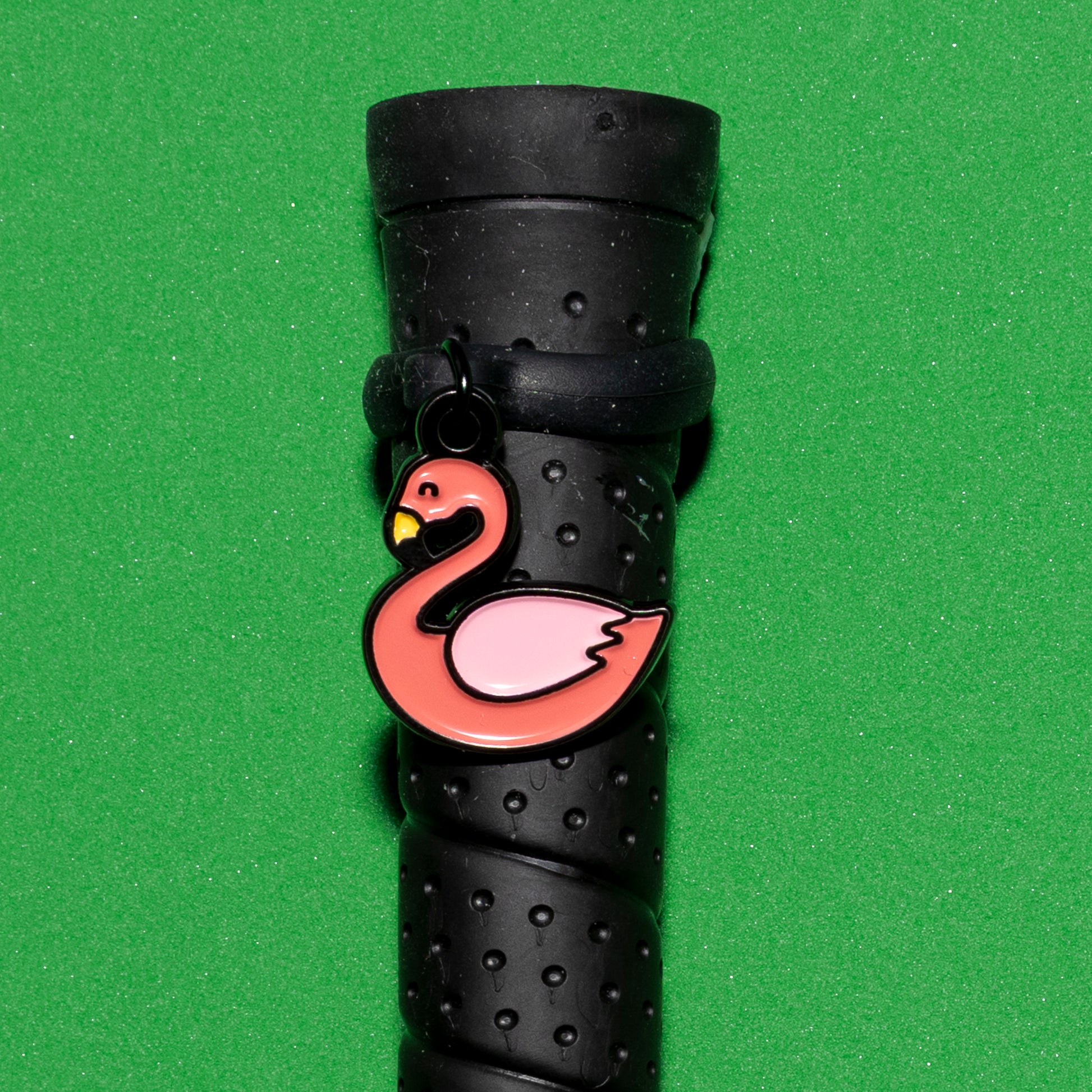 Pinsnickety Flamingo crop charm on a whip handle in front of a colored background