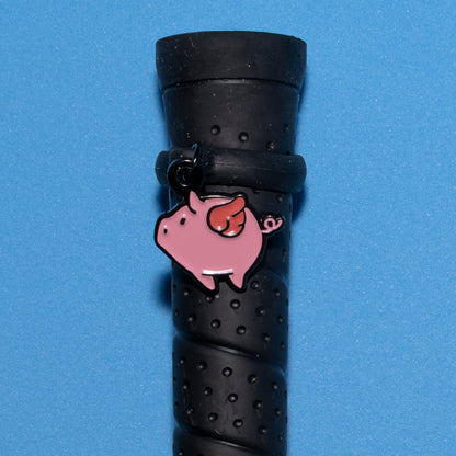 Pinsnickety Flying Pig crop charm on a whip handle in front of a colored background