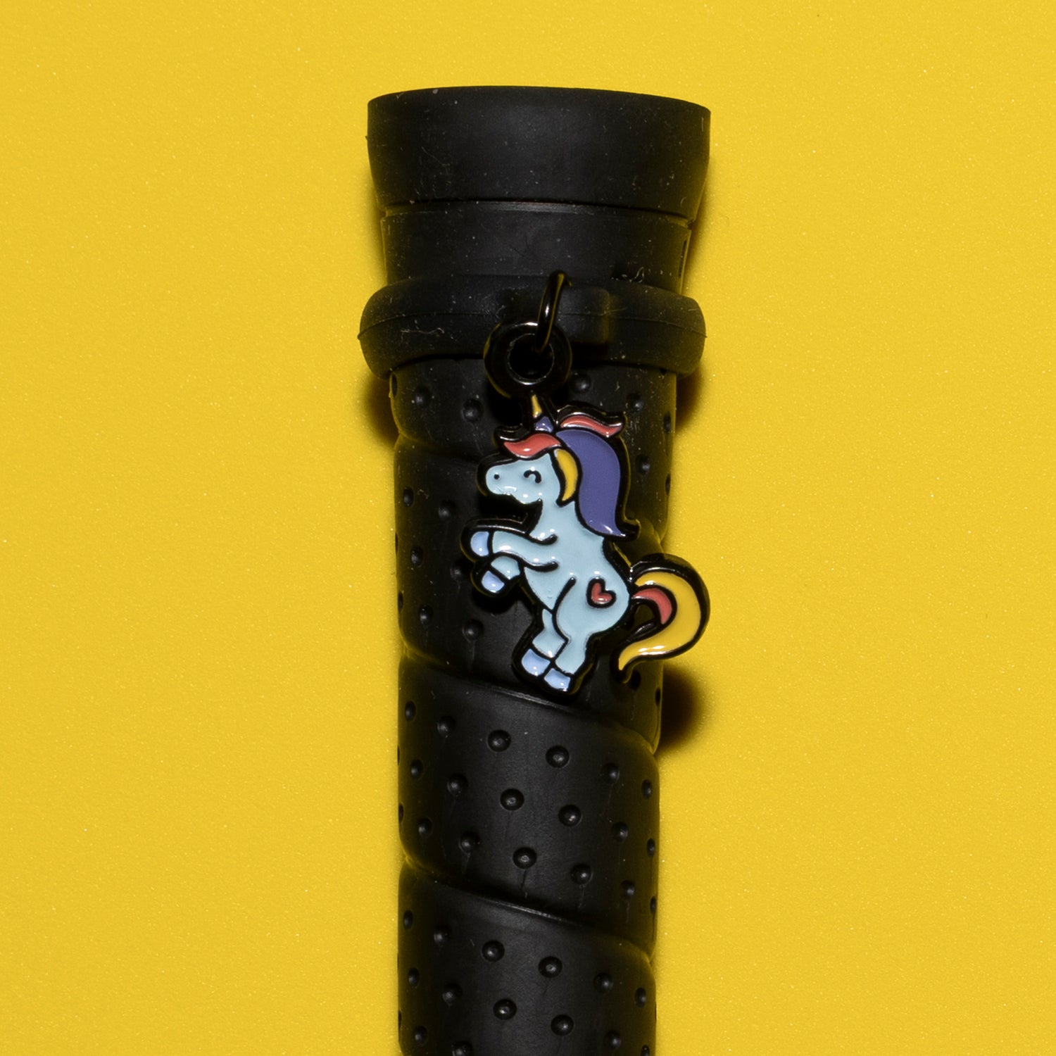 Pinsnickety Flying Unicorn crop charm on a whip handle in front of a colored background