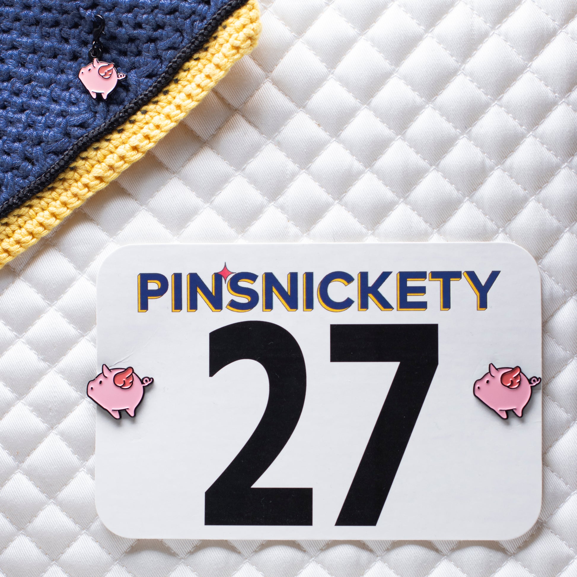 pinsnickety flying pig set, with a flying pig braid and bridle charm on a bonnet and flying pig horse show number pins on a saddle pad