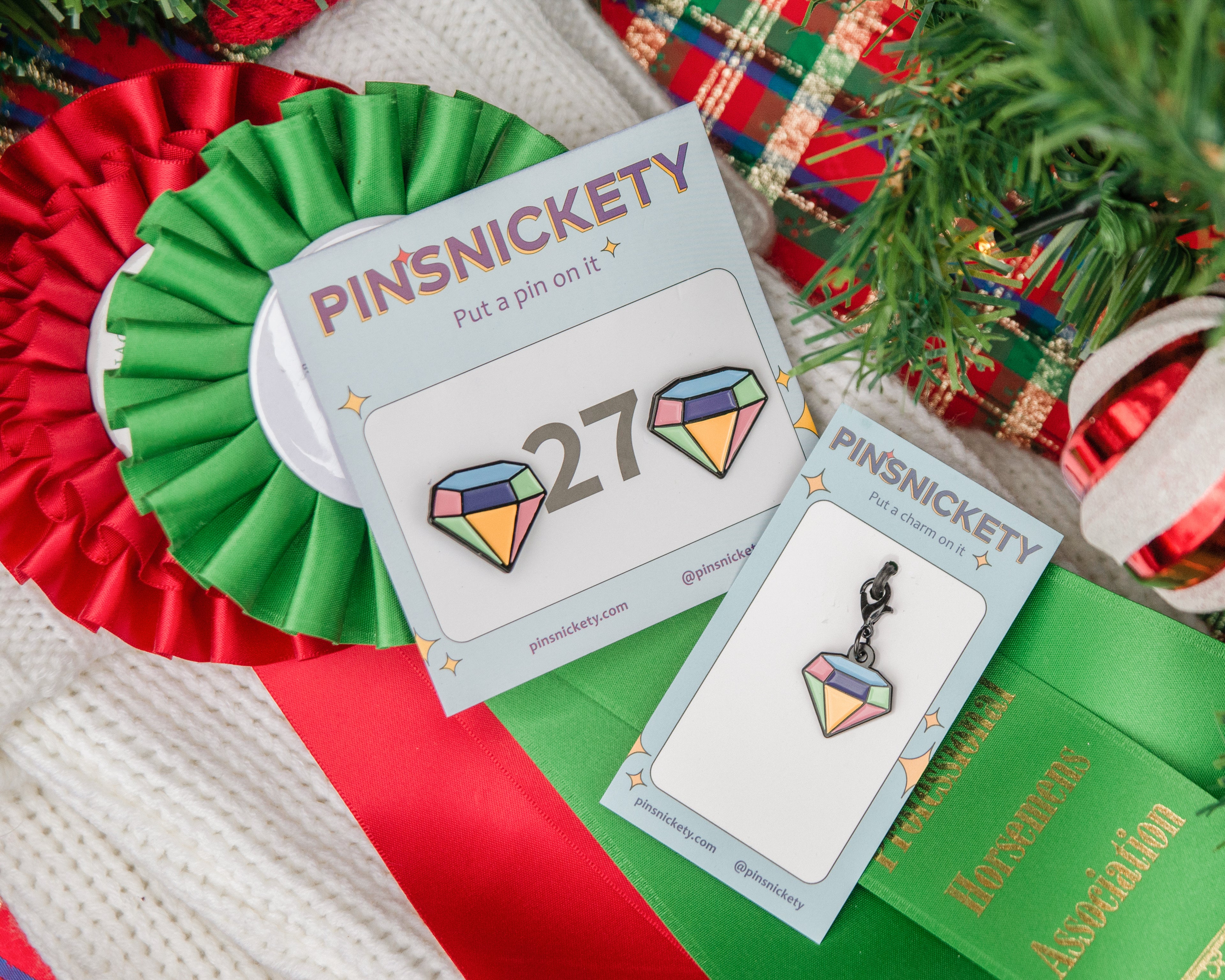 PINSNICKETY number pins and charm with a colorful gen-shaped pin and card against a festive background.