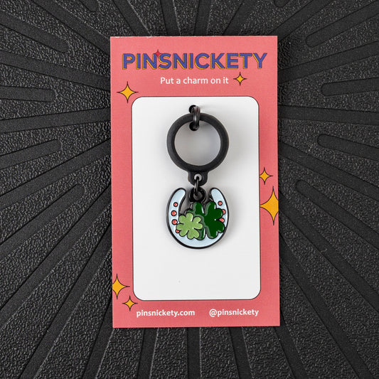 Pinsnickety Horseshoe crop charm in front of a black background