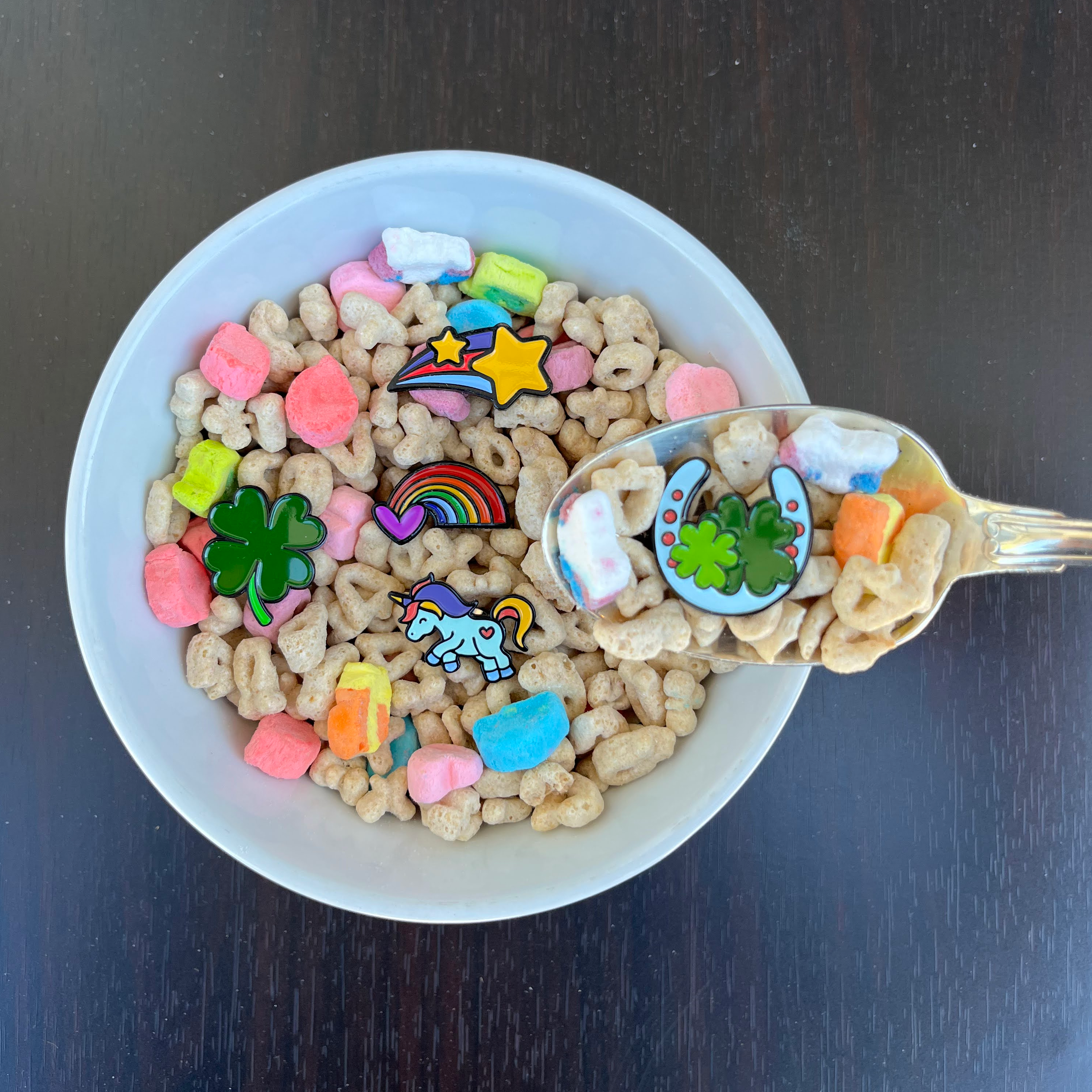 pinsnickety clover, rainbow, flying unicorn, shooting star, and horseshoe horse show number pins in a bowl of lucky charms cereal