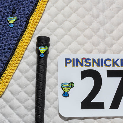 A saddle pad, bonnet and whip decorated with matching Margarita Pinsnickety horse show number pins, a bridle charm and a crop charm.