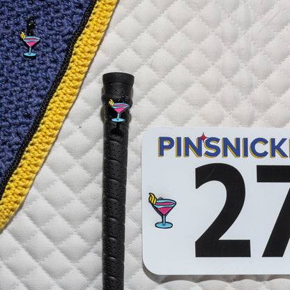 A saddle pad, bonnet and whip decorated with matching Martini Pinsnickety horse show number pins, a bridle charm and a crop charm.