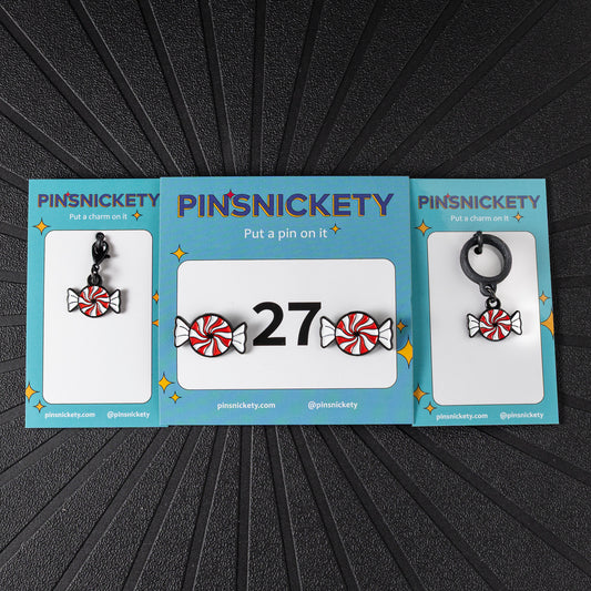 A matching triple combination set with Pinsnickety Peppermint horse show number pins, a bridle charm, and a crop charm in their product packaging on a black background.