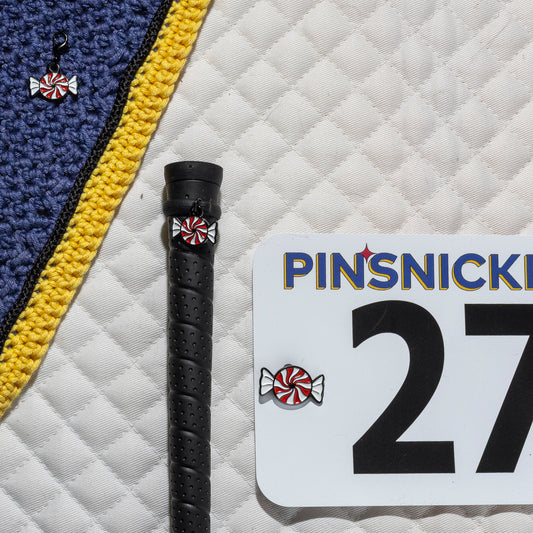 A saddle pad, bonnet and whip decorated with matching Peppermint Pinsnickety horse show number pins, a bridle charm and a crop charm.