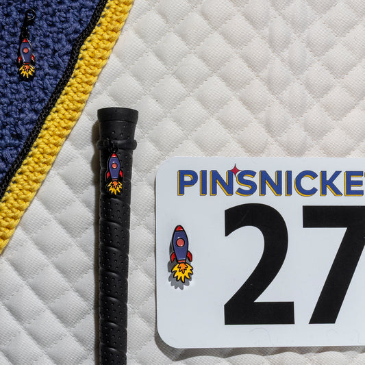 A saddle pad, bonnet and whip decorated with matching Rocket Ship Pinsnickety horse show number pins, a bridle charm and a crop charm.