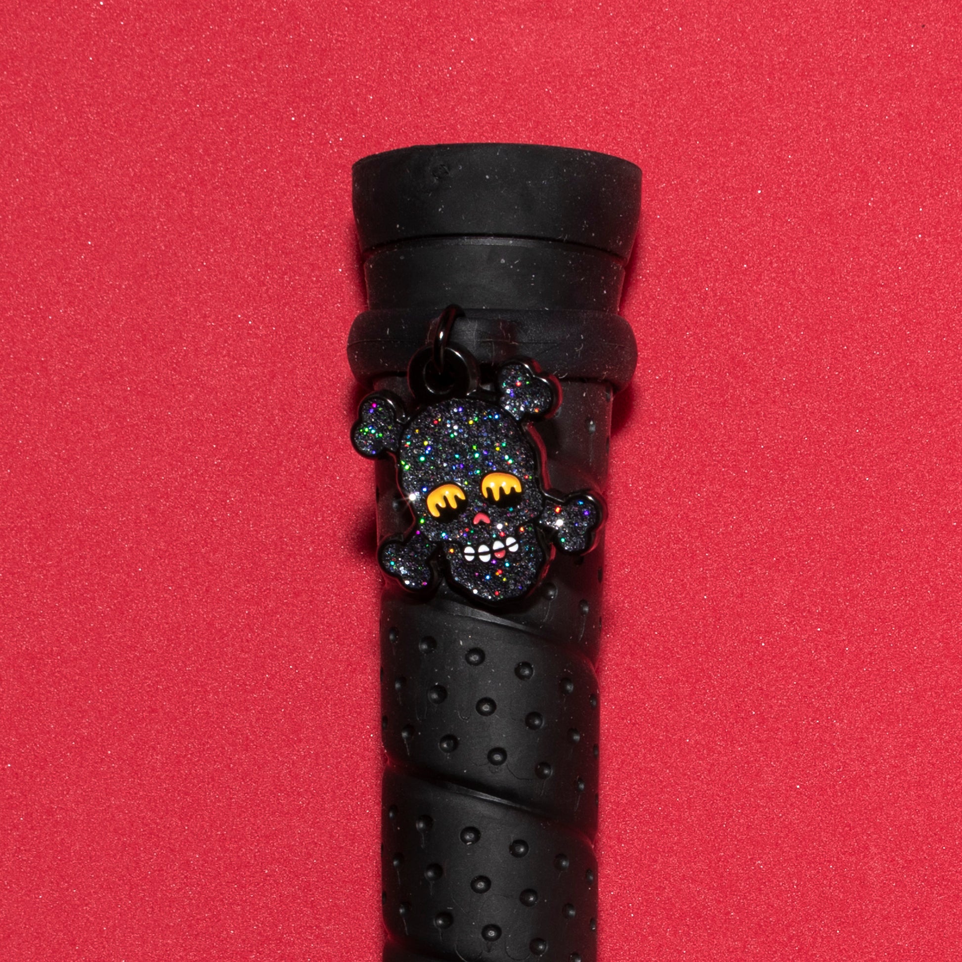 Pinsnickety Skull crop charm on a whip handle in front of a colored background