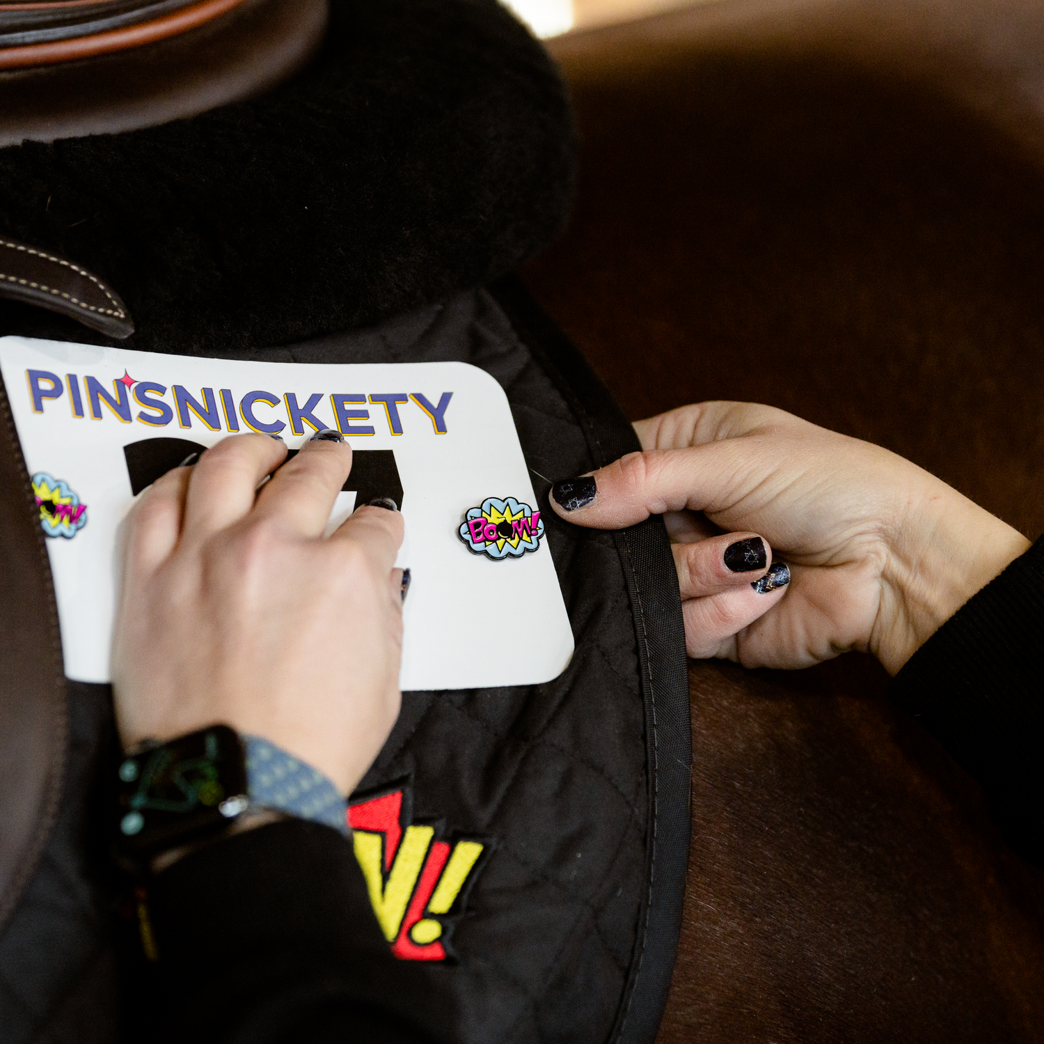 Pinsnickety Boom! horse show number pins being put on a saddle pad