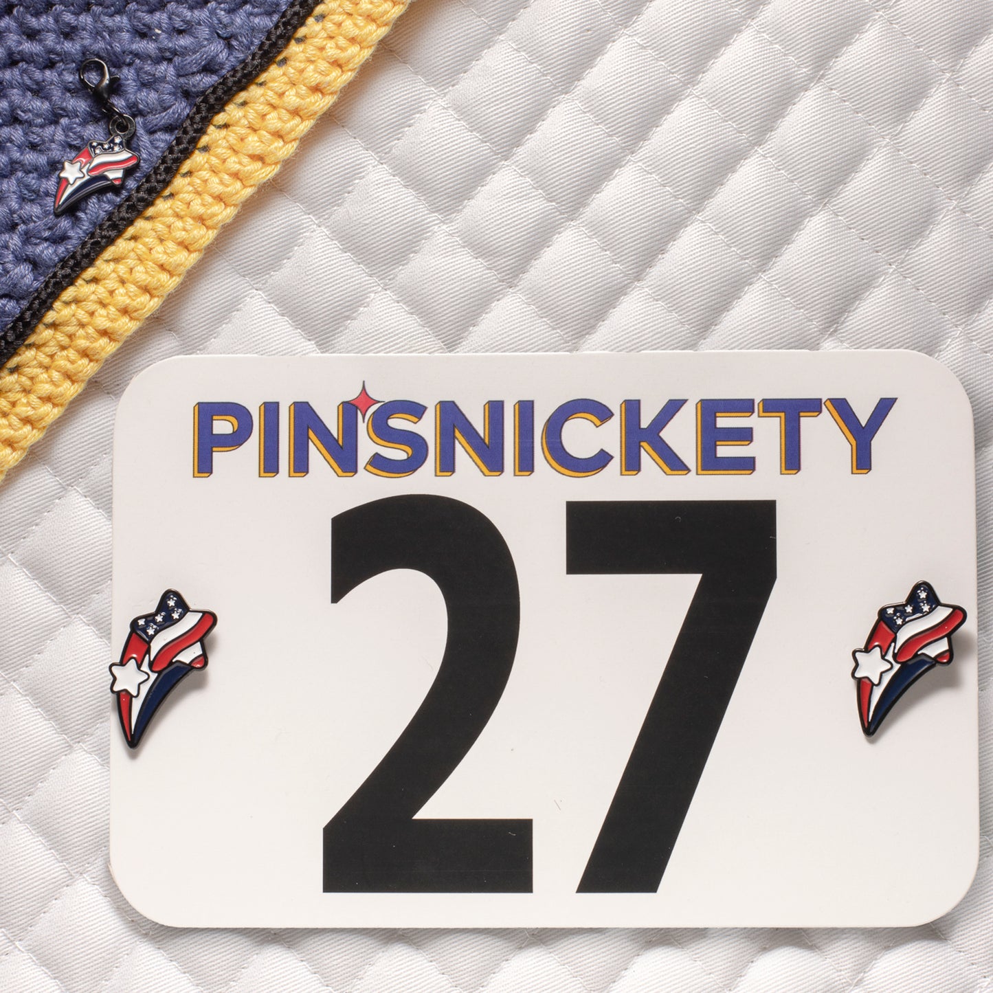 pinsnickety stars and stripes matching set showing a bridle charm on a fly bonnet and horse show number pins on a saddle pad