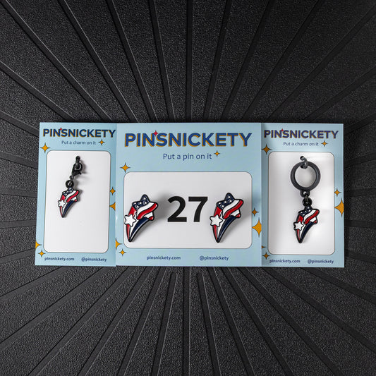 A matching triple combination set with Pinsnickety Stars and stripes horse show number pins, a bridle charm, and a crop charm in their product packaging on a black background.