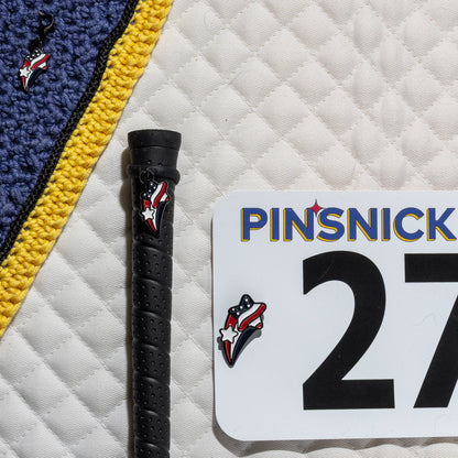 A saddle pad, bonnet and whip decorated with matching Stars and stripes Pinsnickety horse show number pins, a bridle charm and a crop charm.