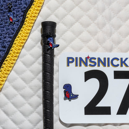 A saddle pad, bonnet and whip decorated with matching T-Rex Pinsnickety horse show number pins, a bridle charm and a crop charm.