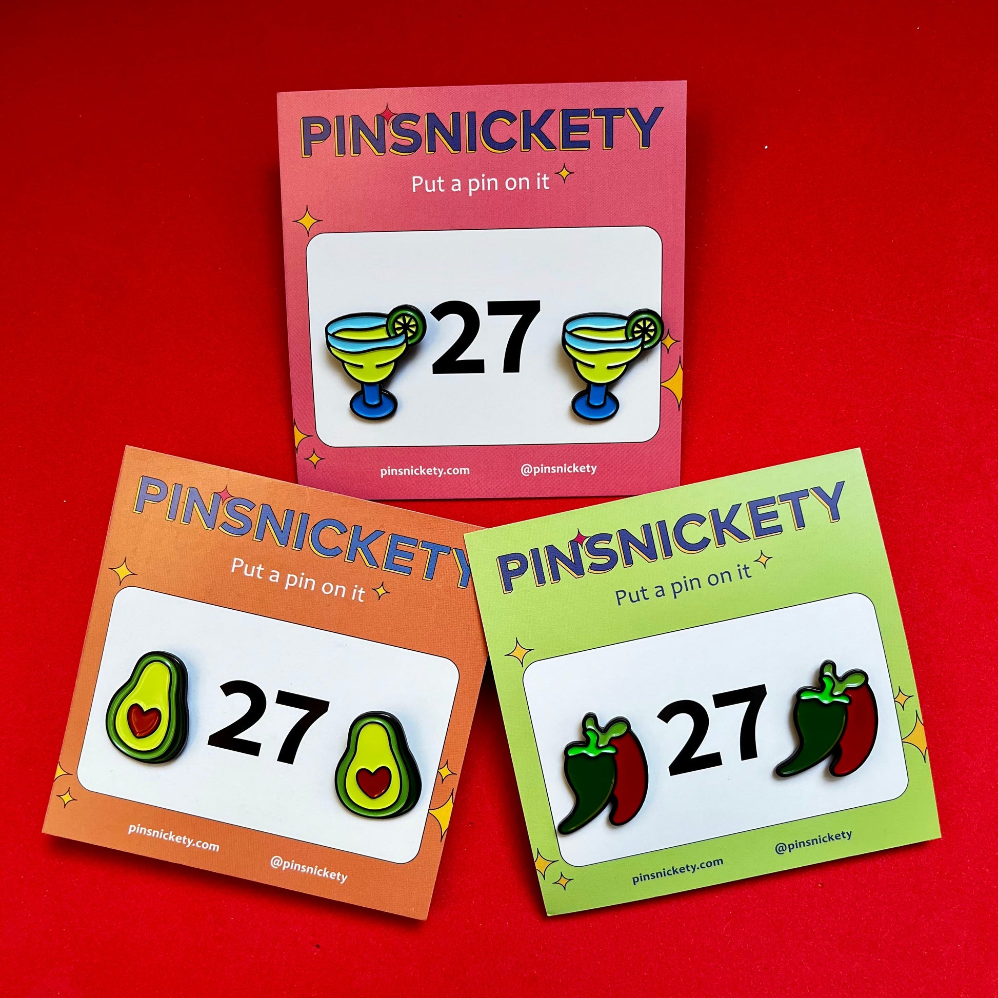 three sets of pinsnickety horse show number pins--the margarita, avocado, and chili peppers--on a red background