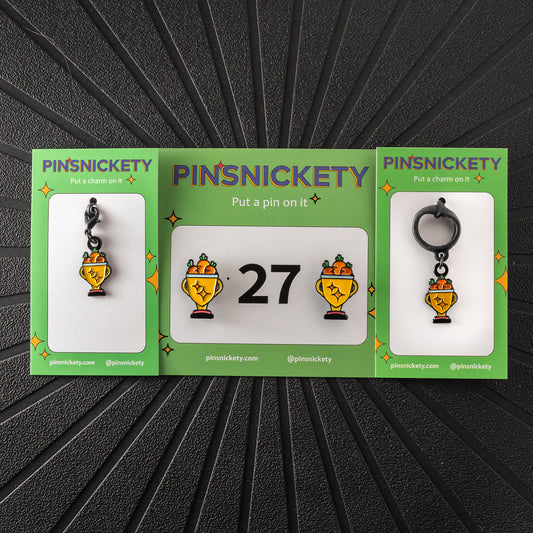 A matching triple combination set with Pinsnickety Trophy horse show number pins, a bridle charm, and a crop charm in their product packaging on a black background.