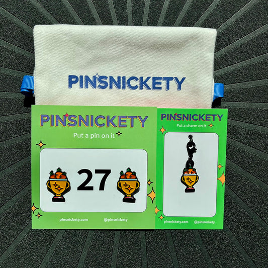 Pinsnickety trophy matching set featuring a pair of trophy horse show number pins, a trophy bridle charm, and a pinsnickety twill storage bag, all on a black background
