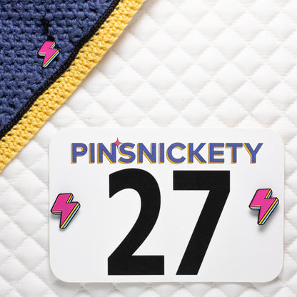 pinsnickety lightning bolt set with a charm on a bonnet and horse show number pins on a saddle pad
