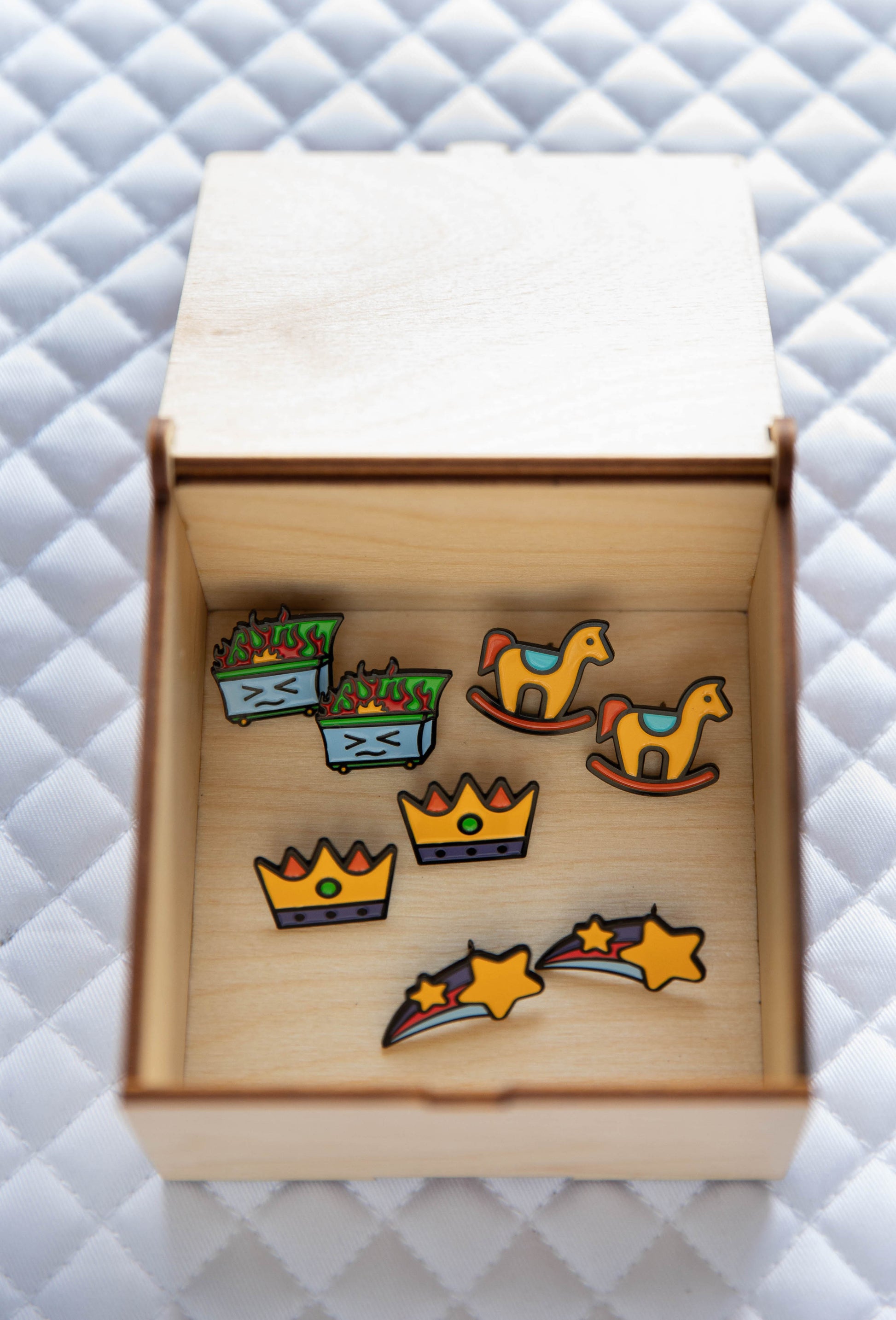 Pinsnickety "Tack" Trunk open with four pairs of pins inside: Shooting Star, Crown, Dumpster fire, and Rocking Horse