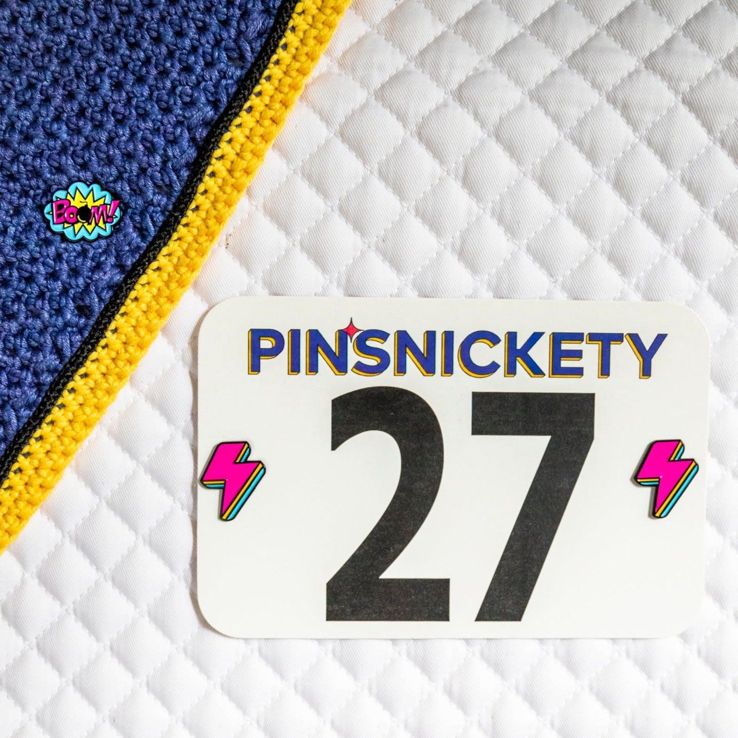 pinsnickety boom and lightning bolt horse show number pins on a bonnet and saddle pad.