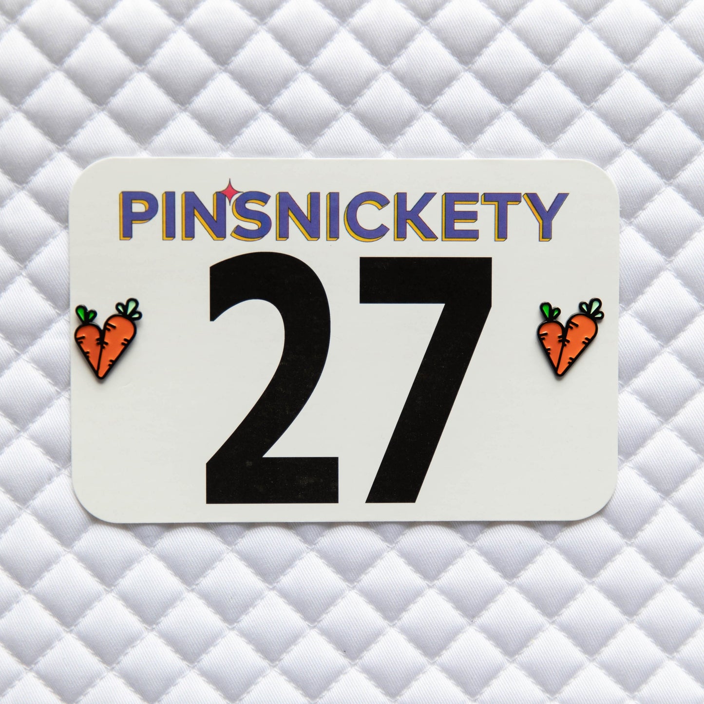 Pinsnickety Carrots horse show number pins on a saddle pad.